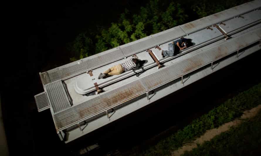 Central American migrants sleep atop a moving freight train as it heads north from Arriaga toward Chahuites, Mexico.