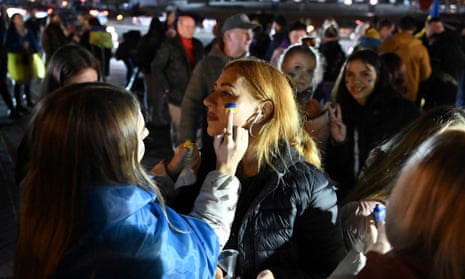 A woman gets the colours of Ukranian flag painted on her face as people gather in Maidan square
