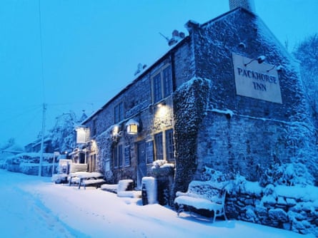 Pub with lights outside at dusk on a snowy day