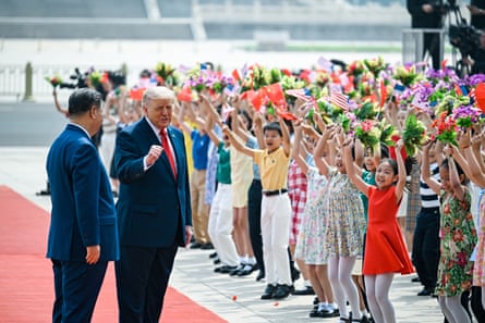 Trump turns to speak to Xi on the red carpet as the children wave flowers and US flags