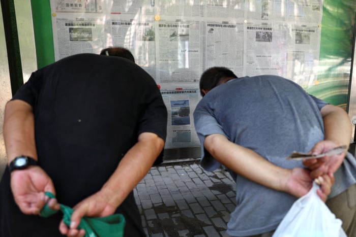 Men read a Global Times report about military exercises near Taiwan at a newspaper stand in Beijing.