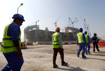Workers walk towards the construction site of the Lusail Stadium.