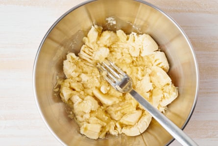 Mashed banana in a mixing bowl with a fork.