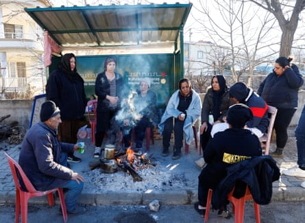 People warm themselves around a fire in Pazarcık.
