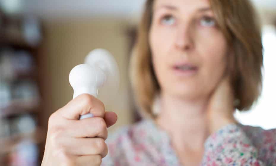 menopausal woman using handheld electric fan