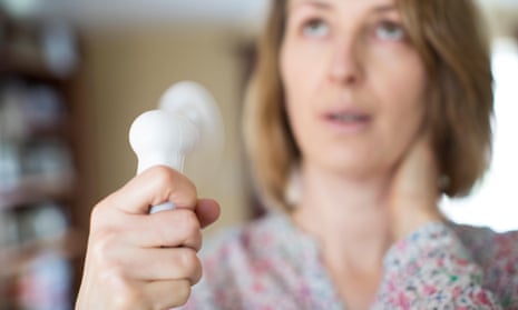 Woman experiencing hot flush from menopause uses electric fan