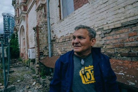 A man walks down a street filled with rubble next to a building without windows