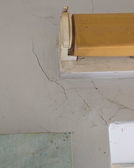 Cracks in the wall near a window blind. There looks to be evidence of previous mould.
