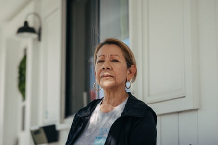 An older woman in front of a house.