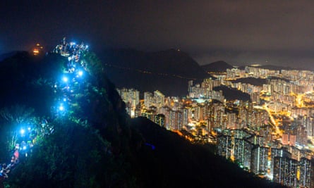 People light up mobile phones on top of Lion Rock.
