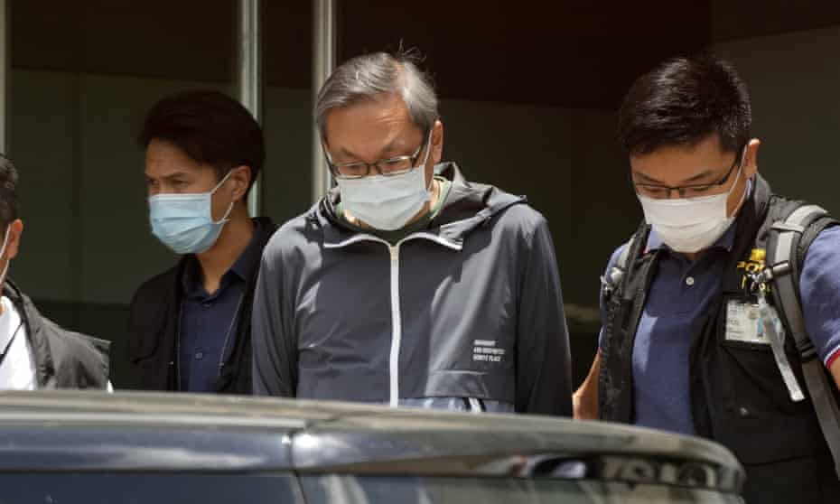 Police officers escort Cheung Kim-hung (center) at Apple Daily’s Hong Kong headquarters in June. 
