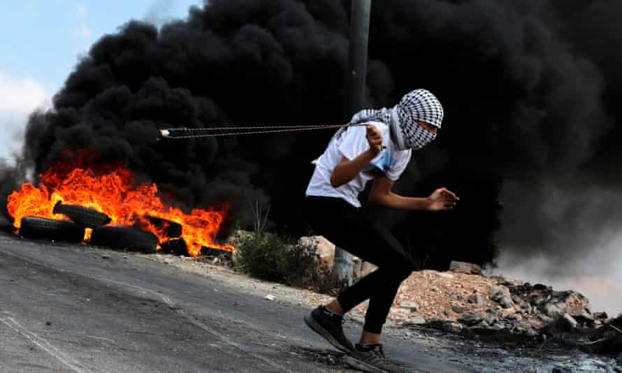 A Palestinian protester uses a slingshot to hurl stones at Israeli troops in the Israeli-occupied West Bank.