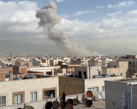 Smoke billows on horizon with buildings in foreground