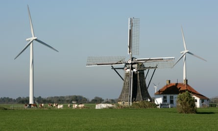 Een historische windmolen tussen moderne windturbines in Nederland.