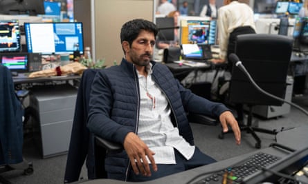 A beaten man with blood on his shirt sits in a chair in an office
