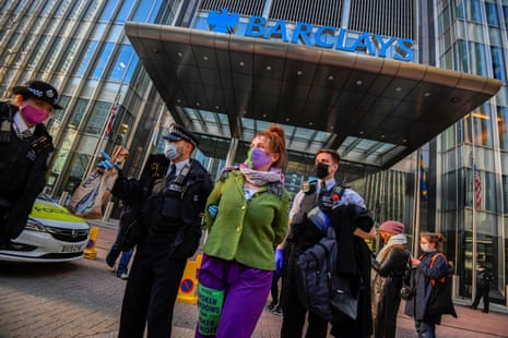 Police officers detain an activist from the Extinction Rebellion, a global environmental movement, outside the Barclays offices in Canary Wharf, London, Britain, April 7, 2021.