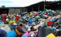 Kenyan workers collect plastic waste for recycling in Nakuru. A pile of plastic items, including colourful buckets and pots, dominates the foreground of the image