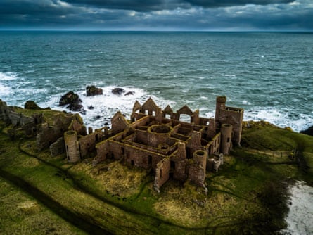 The ruined Slains Castle on a grassy cliff beside a stormy sea