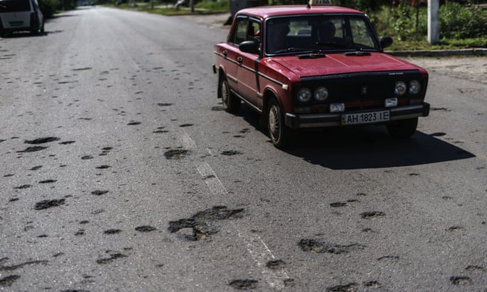 A taxi drives down a road damaged by shrapnel from a May rocket attack in Sloviansk on Saturday.