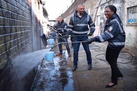 Kemi Badenoch and James Cleverly power-washing a wall.
