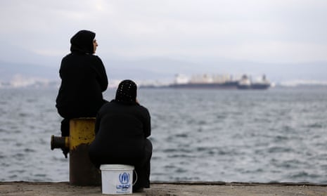 Two women sit on a dock at a refugee camp that houses 3,200 people in a western suburb of Athens