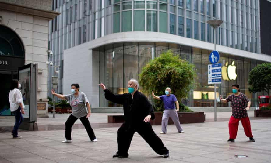 People wearing face masks practise tai chi on a shopping street in Shanghai