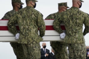 President Joe Biden watches as a carry team moves the transfer case containing the remains of navy corpsman Maxton W Soviak during a casualty return at Dover air force base.