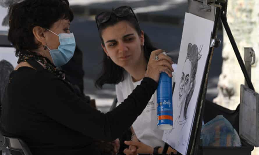 A tourist poses to have her portrait drawn in the city centre.