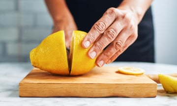 Hands of woman cutting lemons on cutting board.
