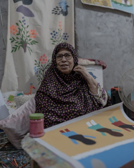 Khaleh Kaniz, a painter, laughs beside a painted artwork of figures