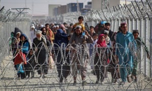 Afghans walk along fences as they arrive in Pakistan through the Pakistan-Afghanistan border crossing point in Chaman yesterday.