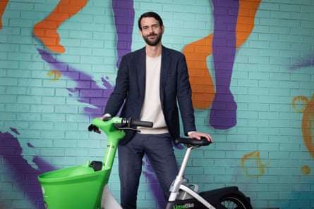 Will Peters stands with a Lime bike in front of a wall covered in street art