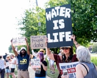 people hold signs against a datacenter under construction