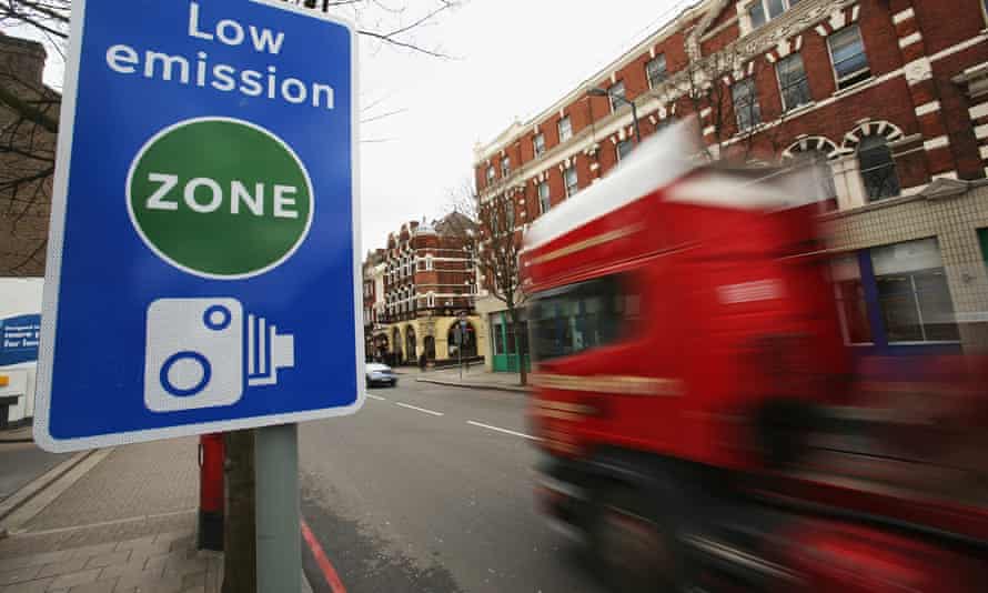 A sign saying 'low emission zone' and a red lorry driving past.