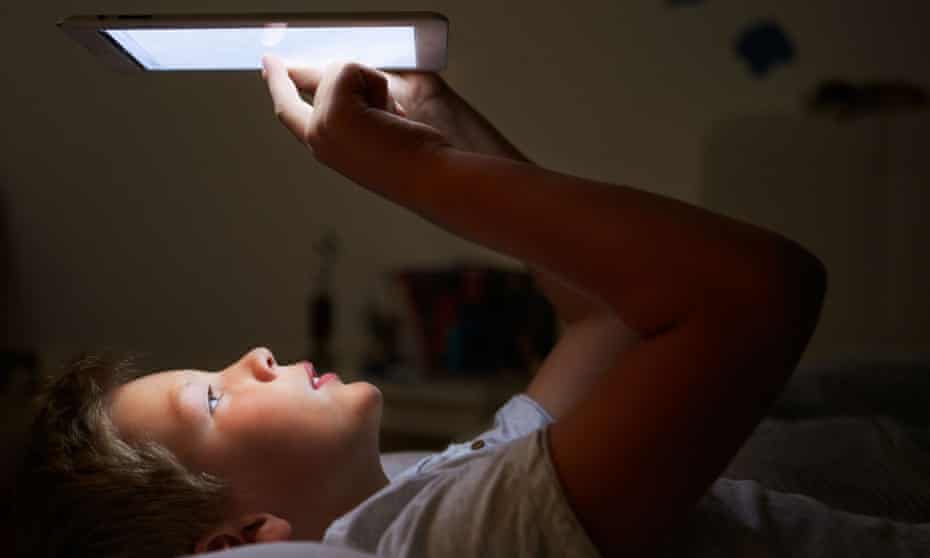 Darkening concerns ... a boy looking at digital tablet in bed.