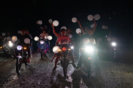 Neighbours form a caravan carrying white balloons behind the truck carrying the Guedez García family