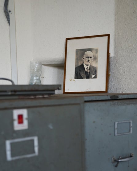 A framed old photograph of a demure gentleman in a suit. The photograph is atop a filing cabinet