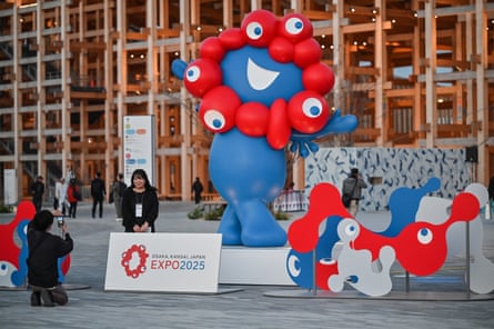 A woman poses for a photo in front of Myaku-Myaku, the mascot of the 2025 Osaka Expo