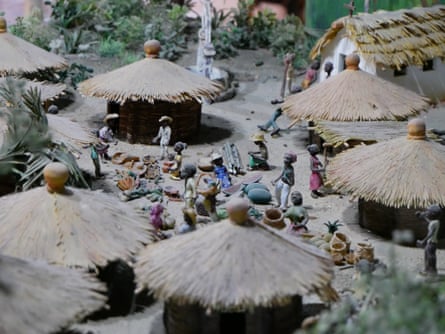 A small diorama of people outside huts. 