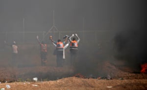 Palestinian paramedics raise their arms at Israeli snipers as they attempt to recover injured demonstrators during the clashes