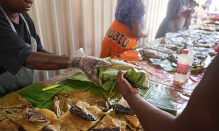 A woman passes a parcel of food to a customer in a market