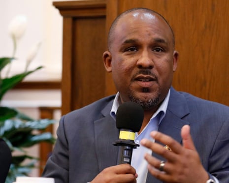 Man in suit coat speaks into microphone.