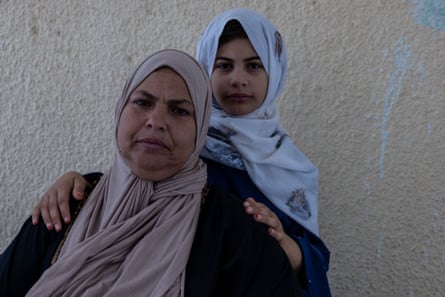 A middle-aged Arab woman with her child behind her, both in headscarves