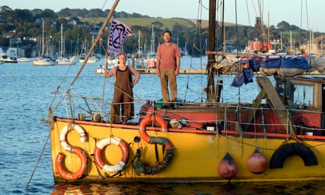 Ocean Rebellion’s Sophie Miller and Rob Higgs on their boat, with SOS spelled out in lifebuoys