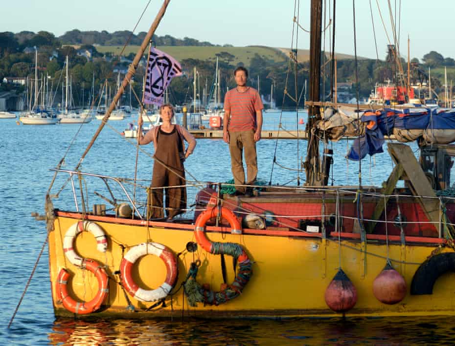 Ocean Rebellion's Sophie Miller and Rob Higgs on their boat, with SOS spelled out in lifebuoys