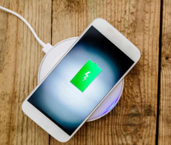 White smartphone charging on a charging pad.