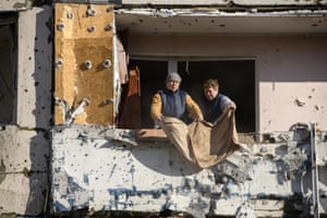 People clear debris at the site of a missile strike at an apartment building in Kyiv, Ukraine