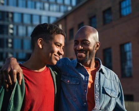 father walking in a city with his arm round his teenage son