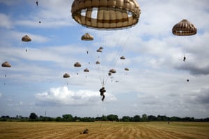 Sixteen parachutists descend towards a field