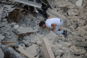 A man searches for victims among damaged buildings